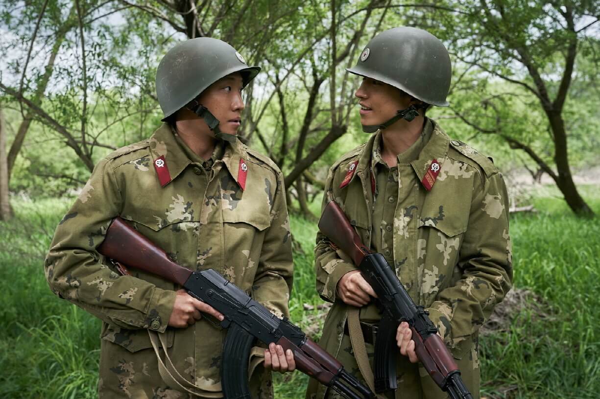 영화 탈주 속 군인2명이 총을 들고 서서 대화하는 모습