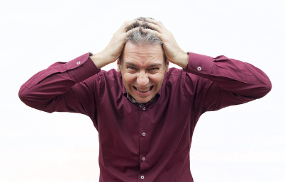 머리를 부여 잡고 있는 중년 남성