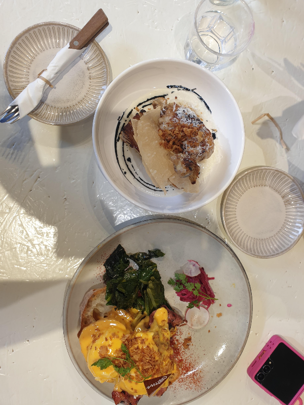 테이블 위에 쿳사 베네틱트와 닭다리 치킨콩피 &amp; 콜리플라워 감자 그라탕이 올려져 있다.