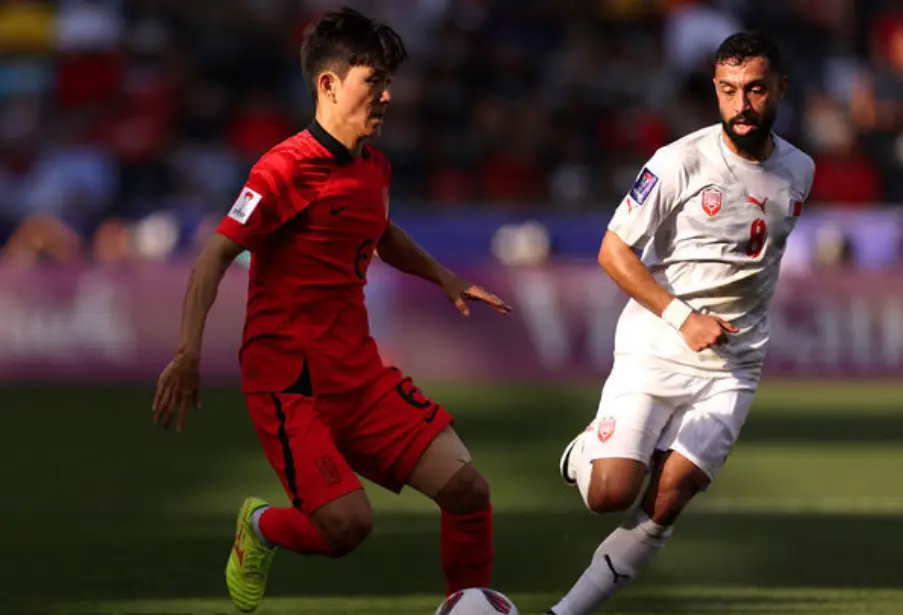 사우디아라비아전- 붉은 유니폼을 입고 달려오는 흰색 상대선수를 제치는 대한민국 축구선수