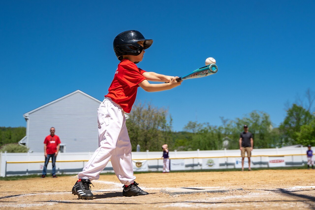 A young baseball player practicing the "tuck and turn" safety move to avoid injury from a pitch.