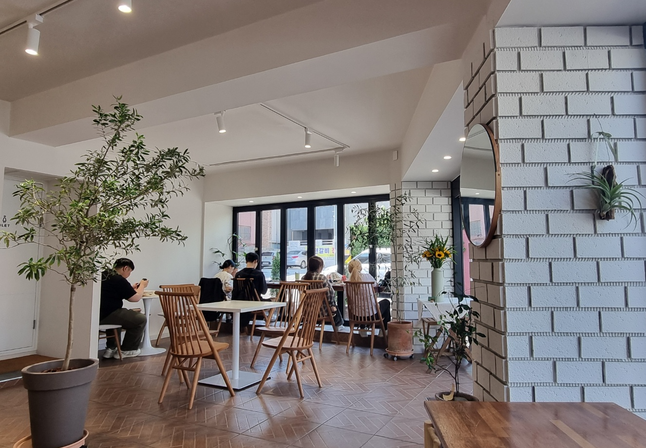 매장 내부는 나무의자와 흰색 테이블, 한쪽 창가에는 일인용 바 형식의 테이블이 설치되어 있습니다.