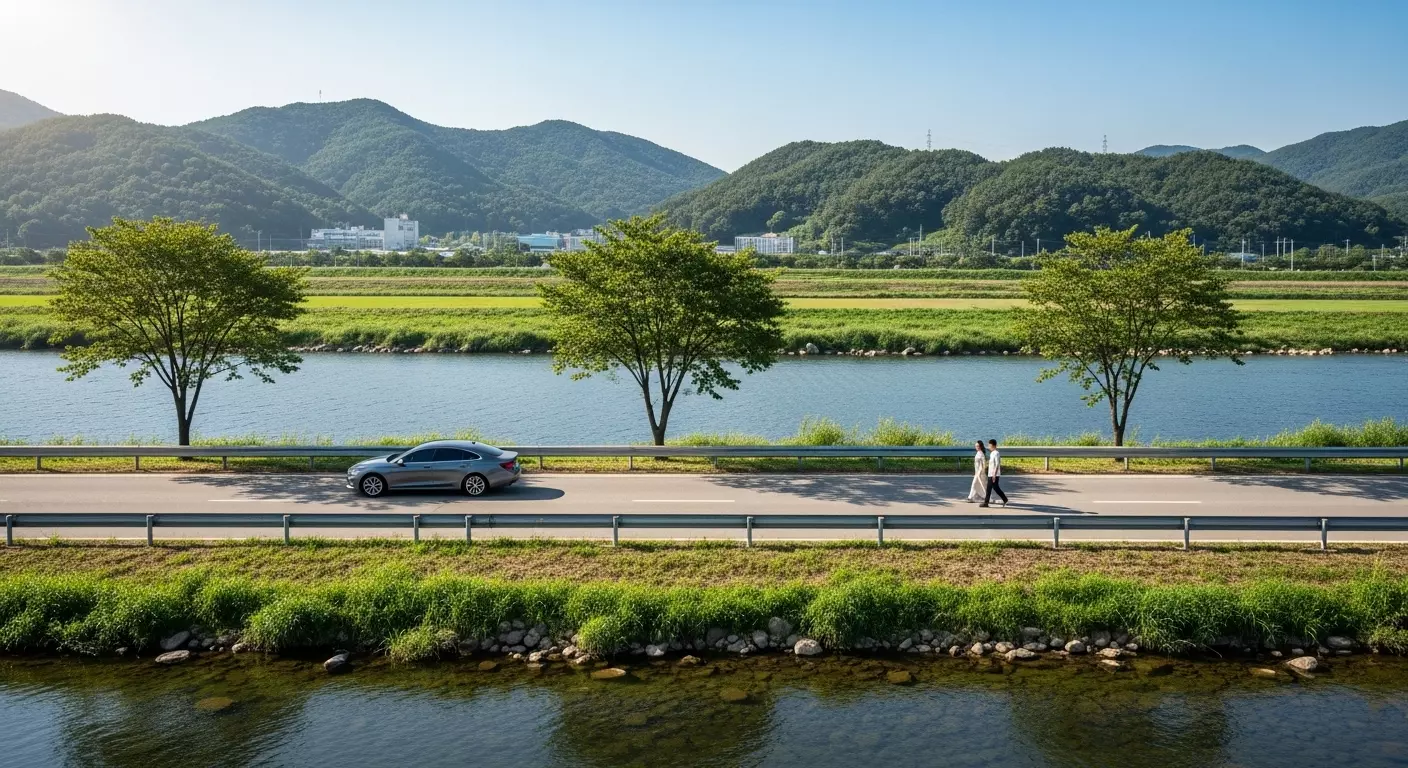 강변을 천천히 달리는 자동차와 그 옆을 걷는 커플 이미지
