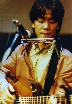 김광석-사랑이라는-이유로-김광석이-무대위에서-하모니카를-목에-걸고-기타-연주에-몰두하고-있는-사진