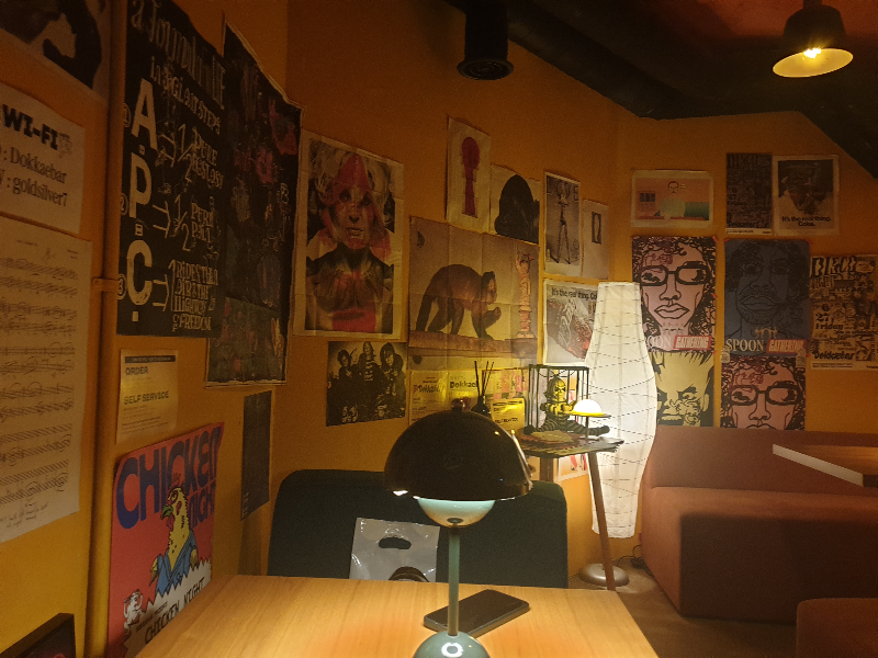 노란색 벽에 다양한 사진과 그림들이 부착되어 있다.