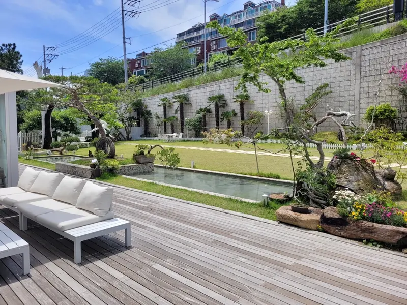 해그리다카페 야외 잔디마당과 연못, 다양한 조경수와 화단, 자연 친화적인 휴식 공간