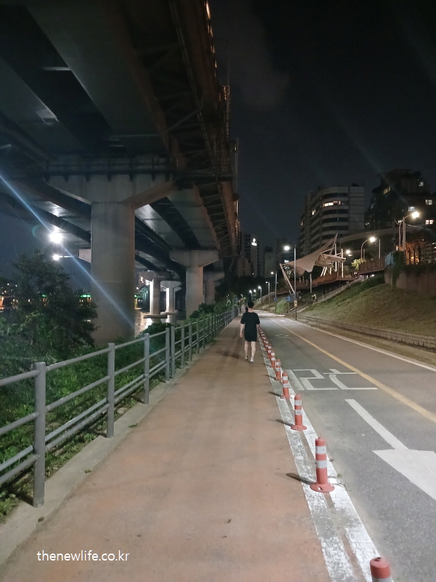 다리 아래 강변 산책로에서 걷는 사람 – 걷기 운동 호흡법과 관련된 실사진