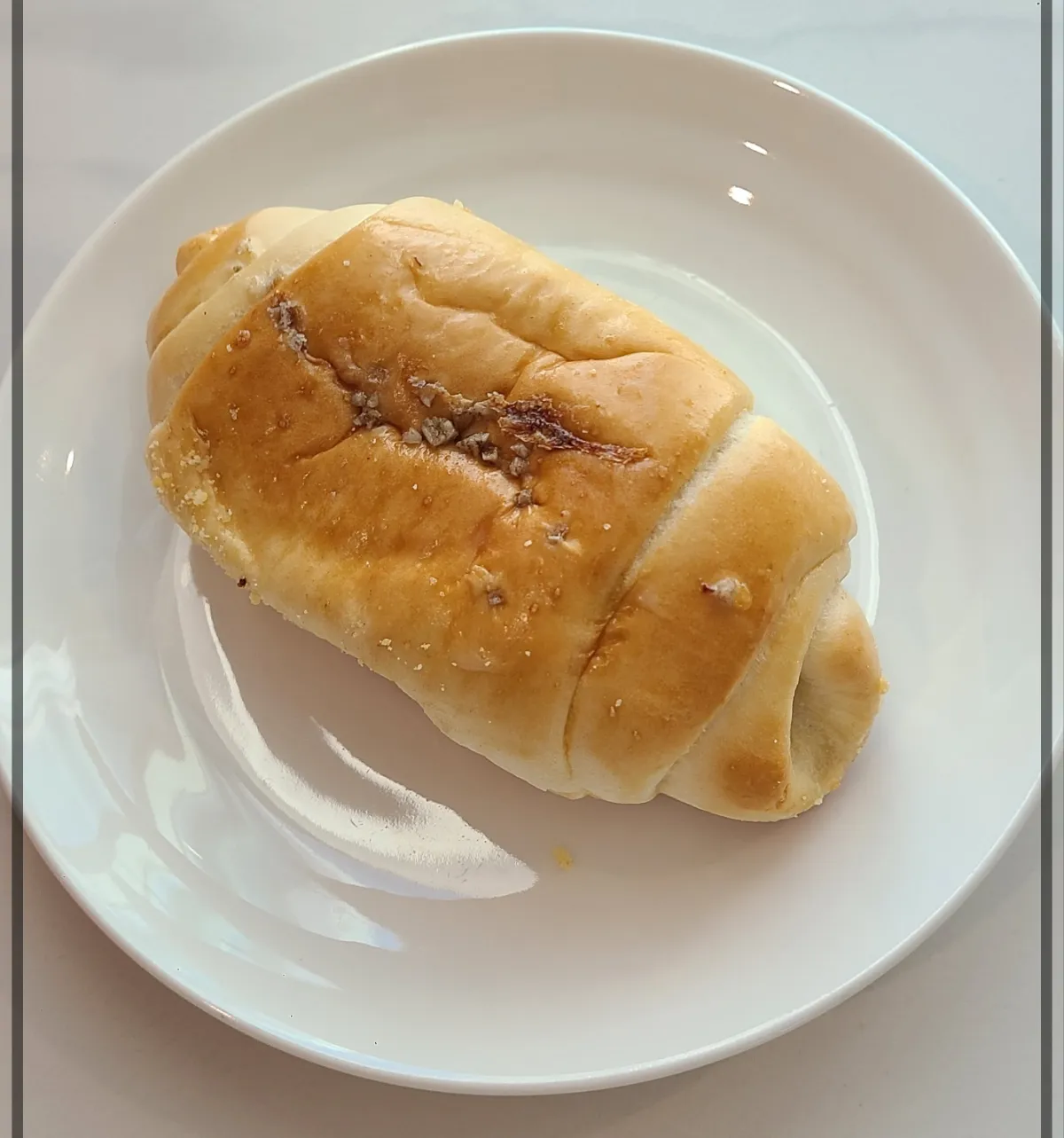 흰접시 위 함초소금빵 빵위에 갈색 함초소금이 뿌려져 있음
