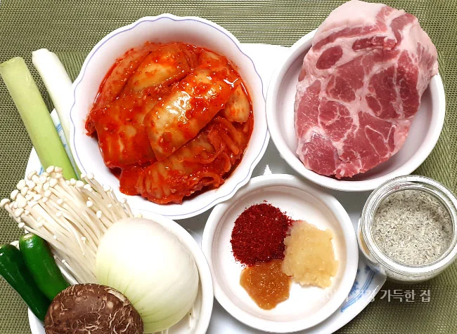 묵은지-목살-김치찌개-만드는방법-준비재료-돼지고기목살-묵은지-두부-양파-대파-표고버섯-팽이버섯-멸치가루-고춧가루-마늘-생강청이-그릇이나-접시에-담겨져있음