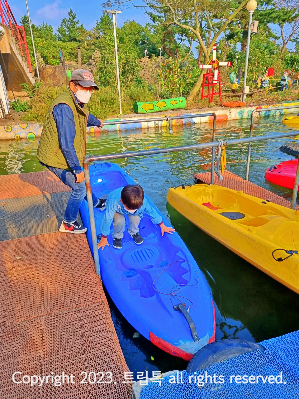 카약선창장에 선생님이 카약을 잡고 있고 아이가 올라타고있다