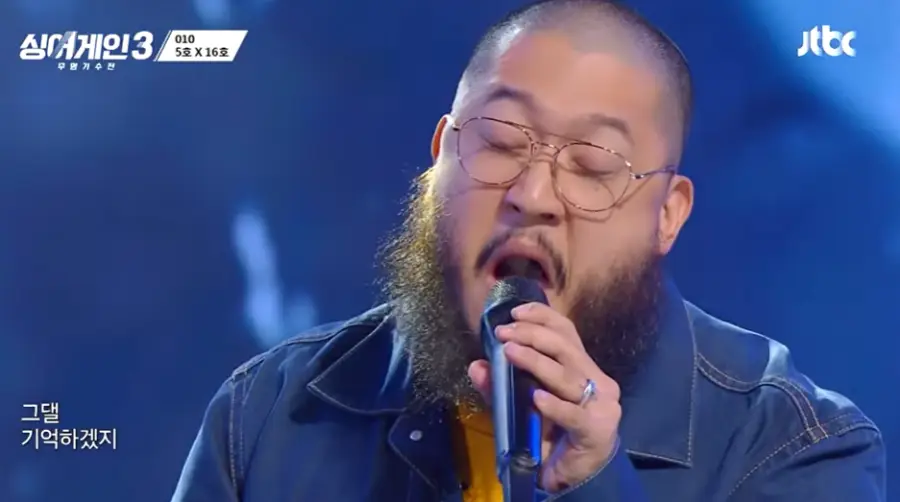 싱어게인3-
파란배경에 파란 쟈켓 수염을 기르고 금테안경을 쓰고 검은 마이크에 노래를 하는 17호