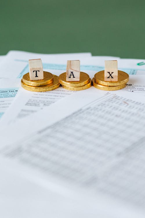 여러장의 문서위에 TAX 라고 동전 위에 적혀있다