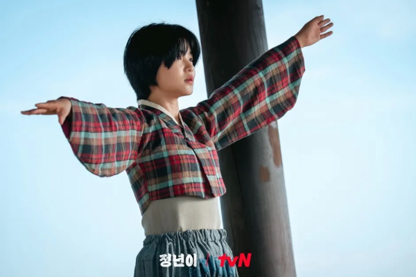 주인공 정년이 (배우 김태리) 체크무늬 저고리를 입고 양팔벌려 먼 곳을 응시하고 있다