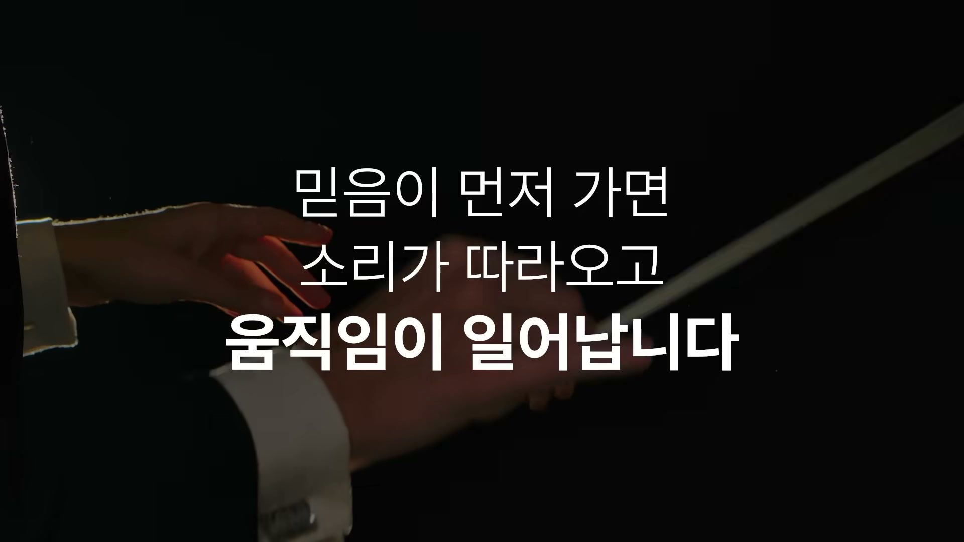 어두운 무대 조명 아래 지휘봉을 든 지휘자의 손 클로즈업 위에 "믿음이 먼저 가면 소리가 따라오고 움직임이 일어납니다" 자막