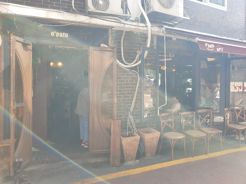 적벽돌로 된 건물 1층. 밖에는 우드 소재 의자들이 놓여 있다.