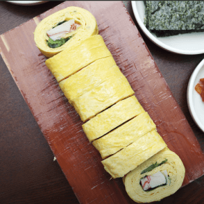 노란 계란말이가 나무접시위에 가지런히 놓인 이미지