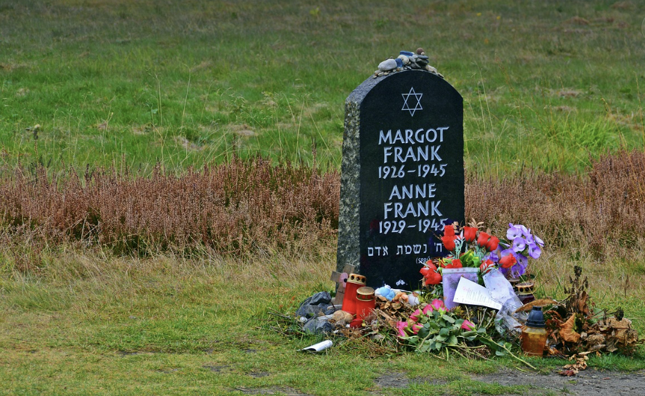 "마르고 프랑크와 안네 프랑크의 이름이 새겨진 공동 묘비. 묘비 앞에는 꽃, 촛불, 돌 등이 놓여 있으며, 배경은 들판으로 둘러싸여 있음."`**

필요하다면 짧은 버전이나 웹 접근성 표준에 맞춘 문구로도 수정해 드릴 수 있어요.