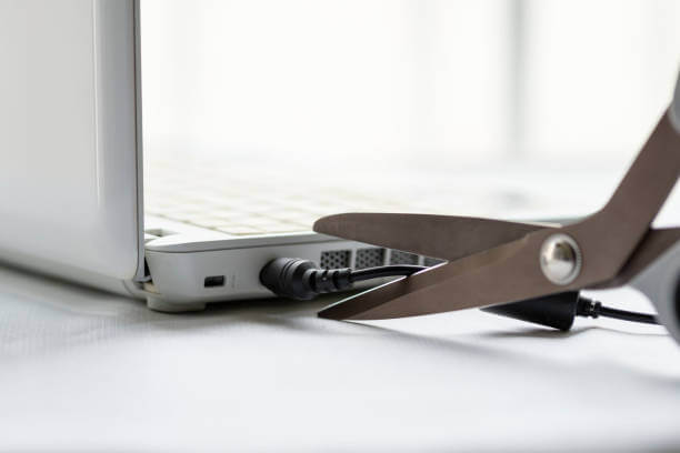 디지털 디톡스를 하기위해 가위로 노트북 충전선을 자르는 사진