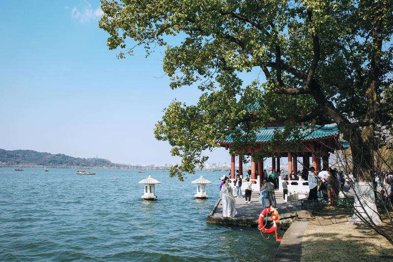 서호 옆 전통 정자에서 한복을 입은 관광객들이 사진을 찍으며 여유롭게 시간을 보내는 모습
