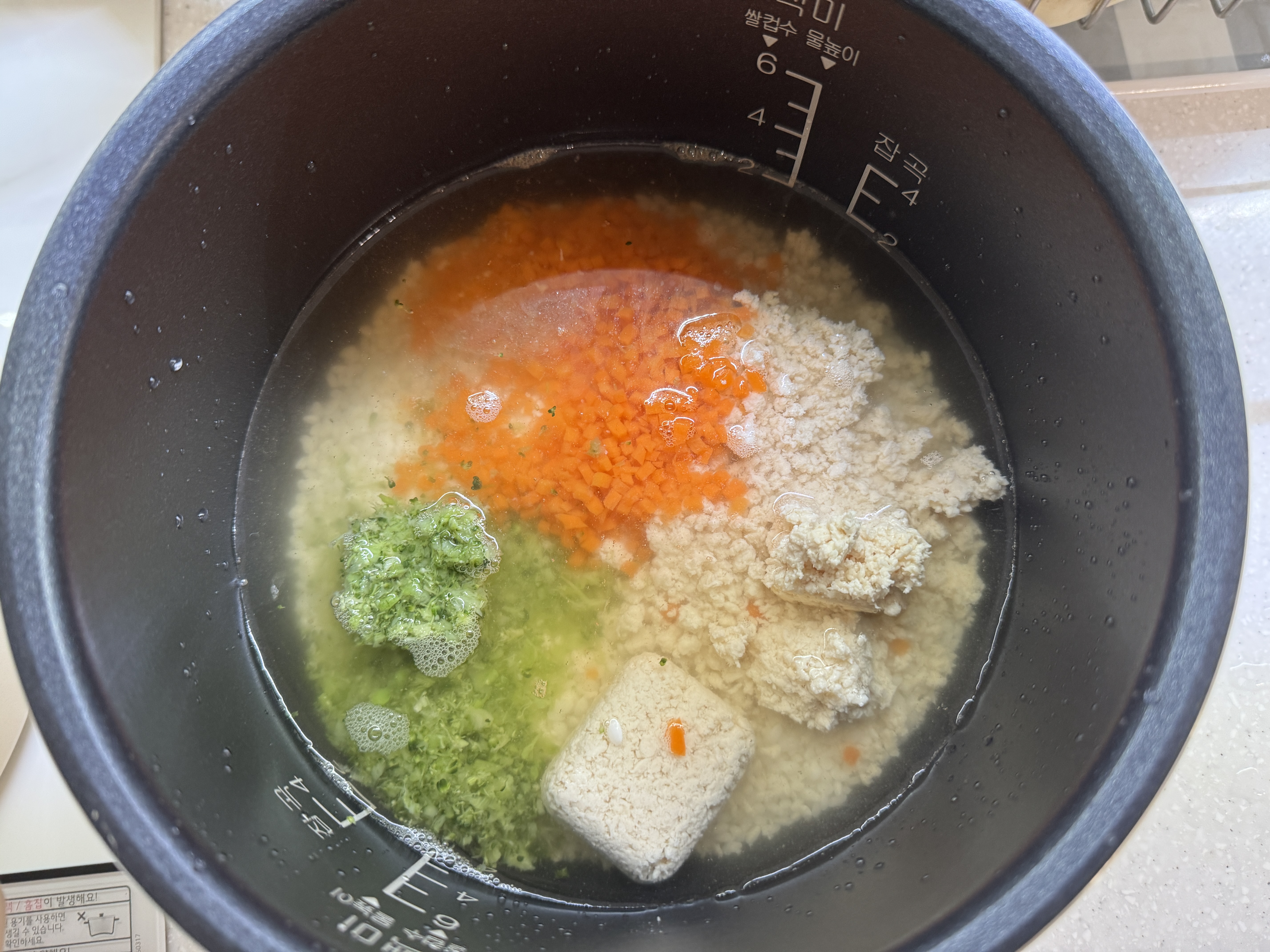 밥솥에 불린 쌀과 채수&amp;#44; 닭고기&amp;#44; 당근&amp;#44; 브로콜리를 넣은 사진