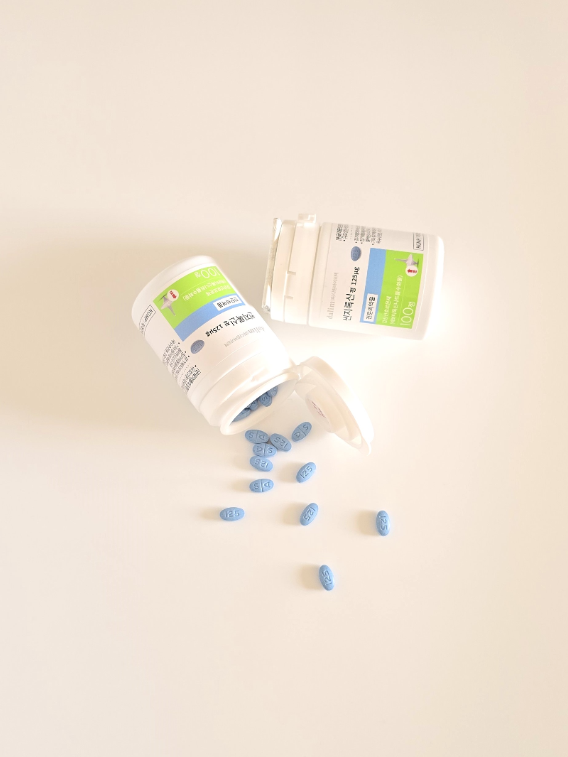 흰색 플라스틱 약병에서 쏟아져 나온 파란색 타원형의 갑상선 호르몬제(씬지로이드 125mcg) 알약들