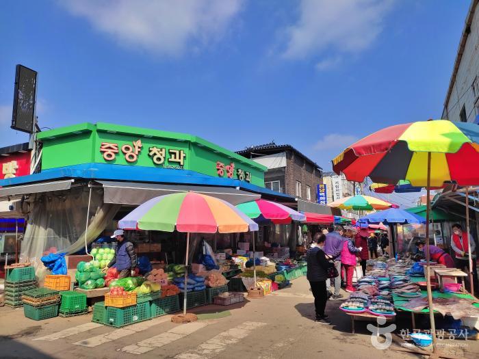 시장 파라솔 아래 각종 야채와 생선들이 널려있다.