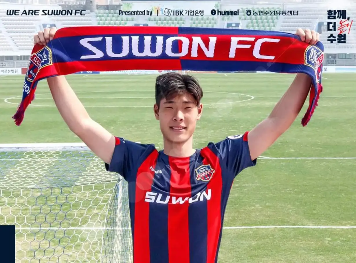 이영준-붉은 유니폼을 입고 축구운동장에서 수원이 적힌 타월을 두손으로 들고 있는 이영준