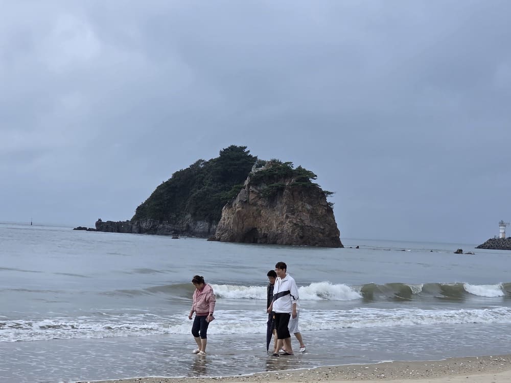꽃지해수욕장 바위섬과 파도 앞을 걷는 여행객들