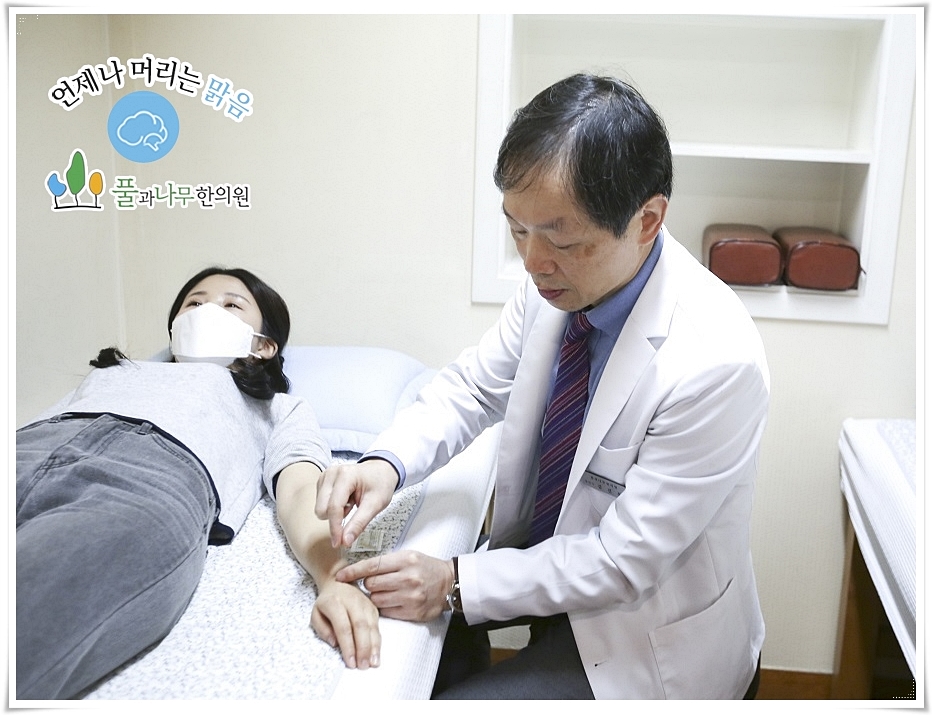 누워 있는 환자의 손 등에 침을 놓고 있는 한의사의 모습