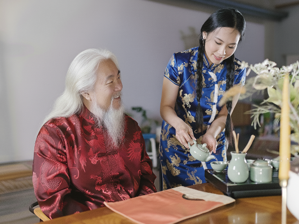 아버지에게 딸이 차를 내리고 있다. 아버지는 붉은색 딸은 푸른색 옷을 입고 있다.