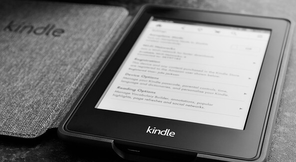 The Kindle Amazon e-book reader is spread out on the table.