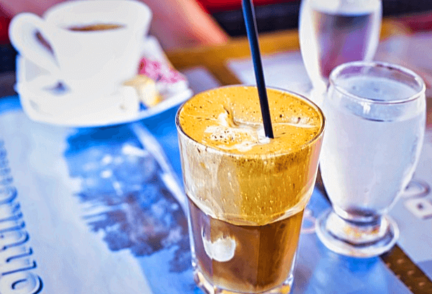 파란 공책 위에 아이스 카페라떼가 담긴 유리컵과 시원한 물이 담긴 유리컵, 반대편에는 하얀 커피잔에 따뜻한 블랙커피가 담겨있다.