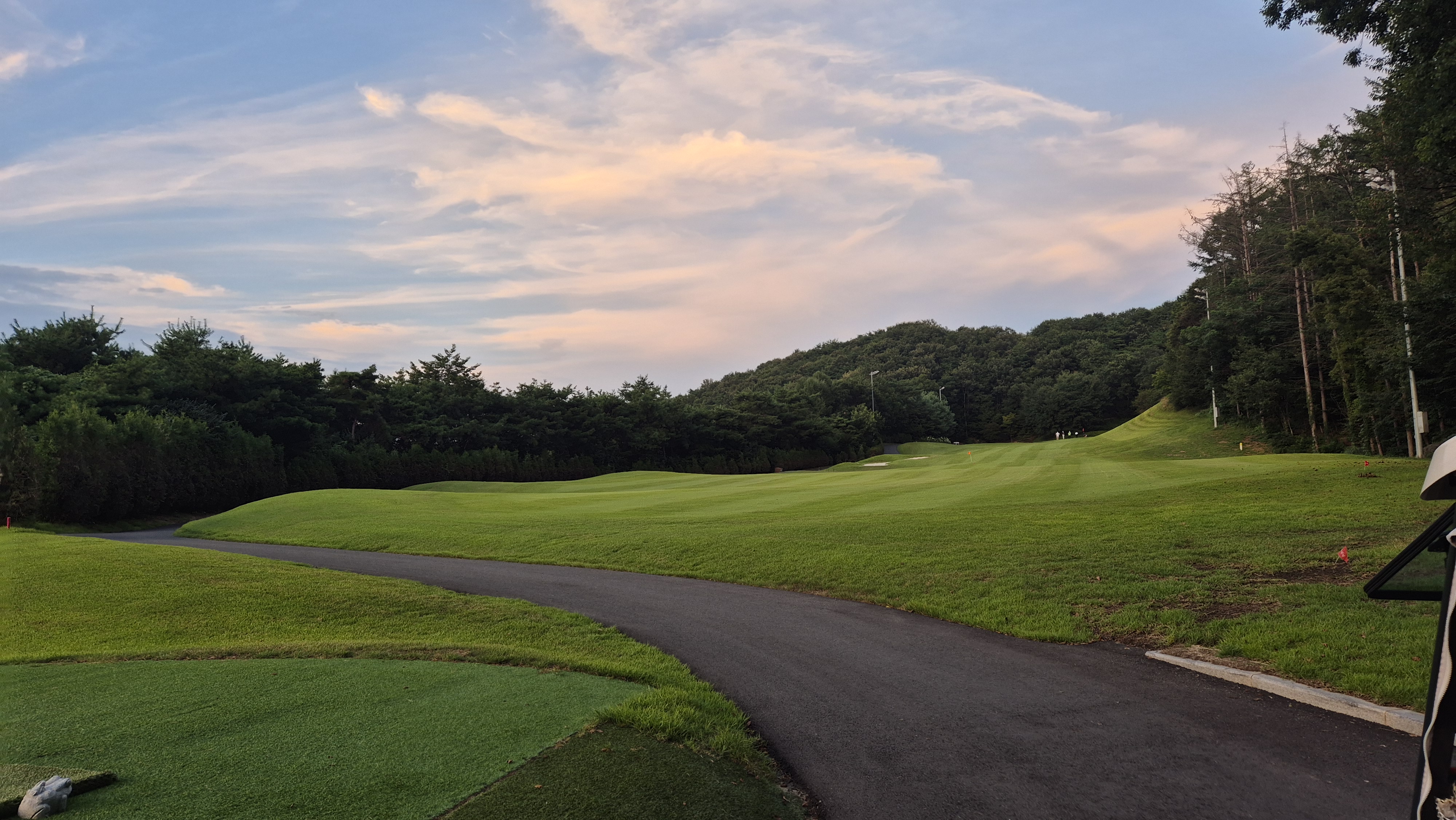 골프장에서 해 질 무렵 붉게 물든 하늘과 완만한 페어웨이 풍경