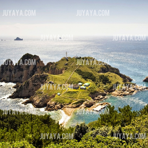 A stunning view of Somaemuldo Island with a lighthouse at the top of the hill, offering a serene atmosphere and scenic views of the coast.