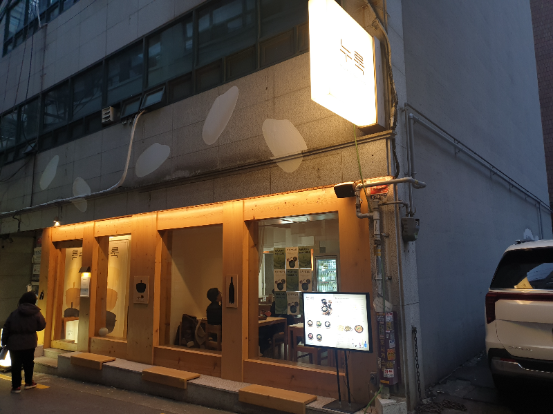 노란 조명이 감싸는 솥밥 다이닝 누룩 전면