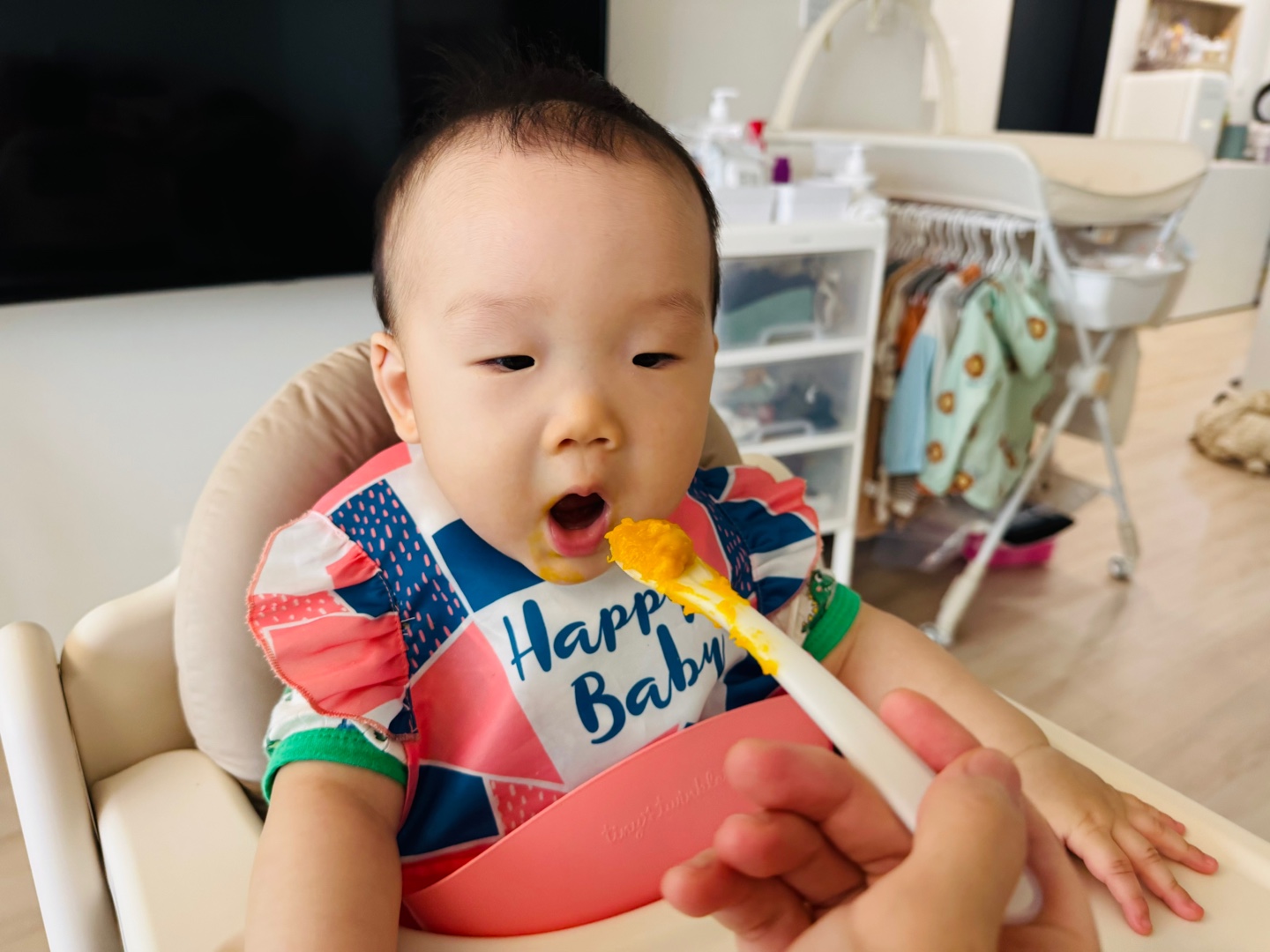 찬솔이가 노란 단호박바나나매시를 숟가락으로 먹고 있는 아침 식사 장면