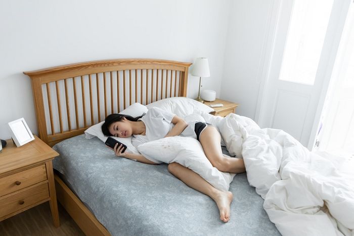 밤새 침대에 누워서 웹툰을 보는 사람의 모습