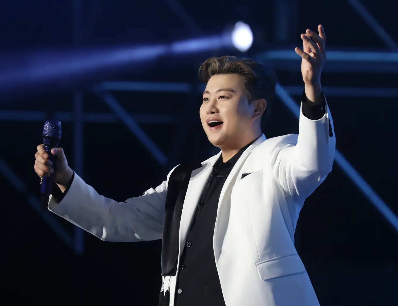 파란무대배경 흰옷을 입은 김호중이 두팔벌린채 미소짓는 모습