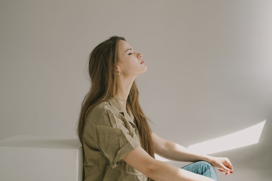 Side profile of a young woman sitting indoors, lost in thought with eyes closed.