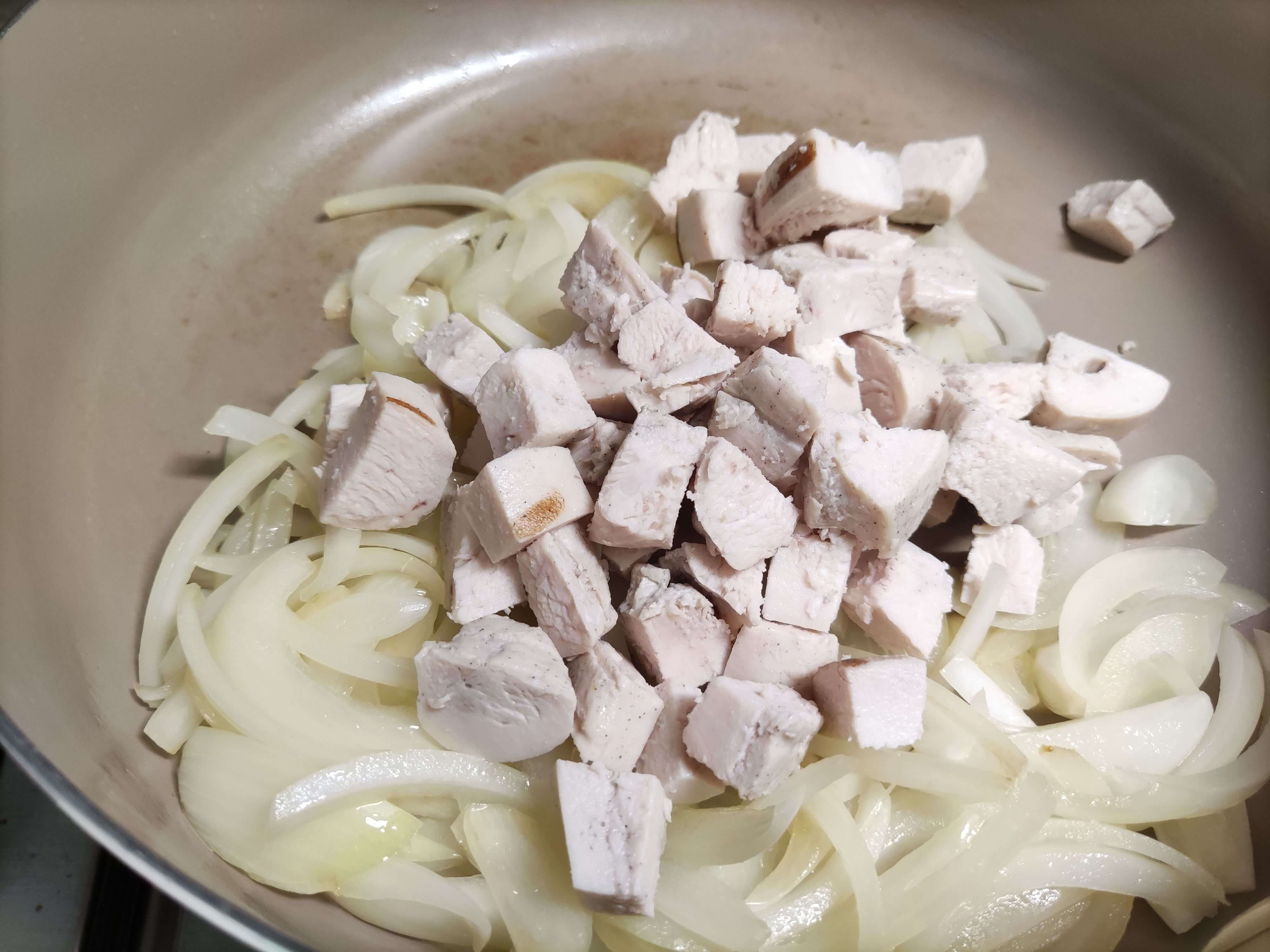 볶아진 양파 위에 한입 크기로 자른 닭가슴살을 넣는 모습