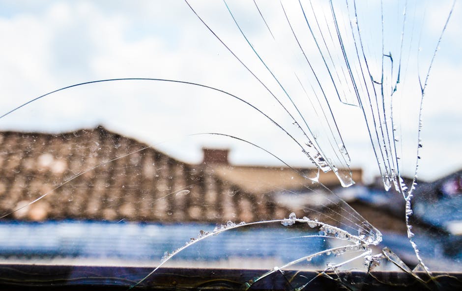 Close-up of cracked glass window revealing a blurred scenic view outdoors.