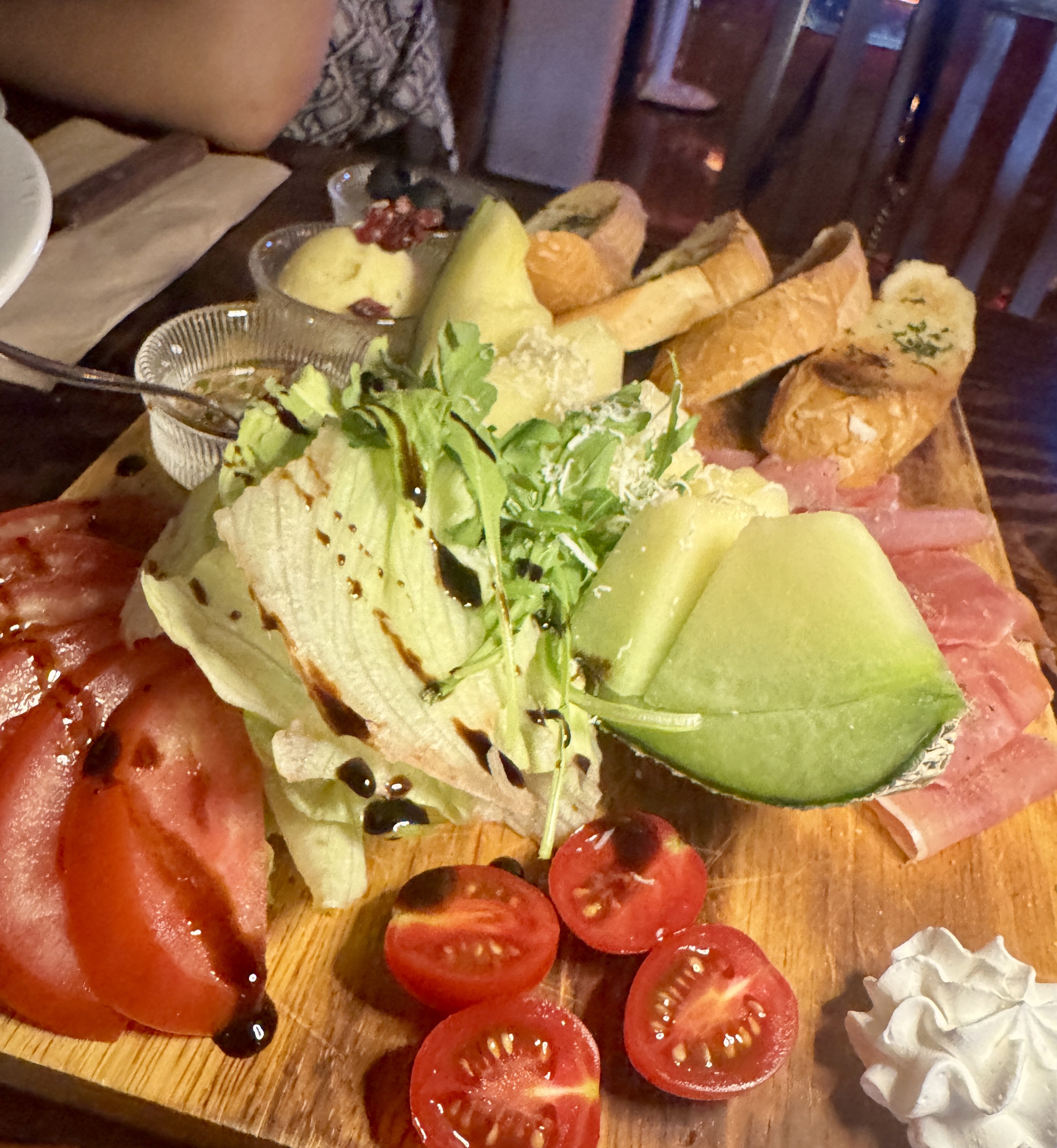 논현동 와인바에서 주문한 세라뇨 하몽 플레이트. 멜론&amp;#44; 하몽&amp;#44; 바게트&amp;#44; 채소&amp;#44; 토마토 등 다양한 재료가 넓은 우드 플레이트에 보기 좋게 담겨 있다.