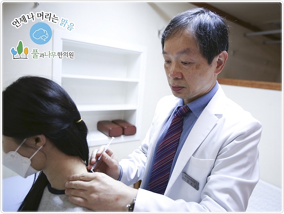 환자의 목 귀에 약침을 놓고 있는 한의사의 모습