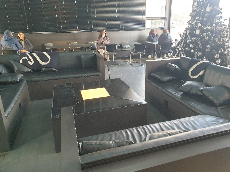 중앙 커다란 정사각형 모양으로 소파가 배치되어 있고 벽면에는 테이블이 일렬로 구성되어 있다.