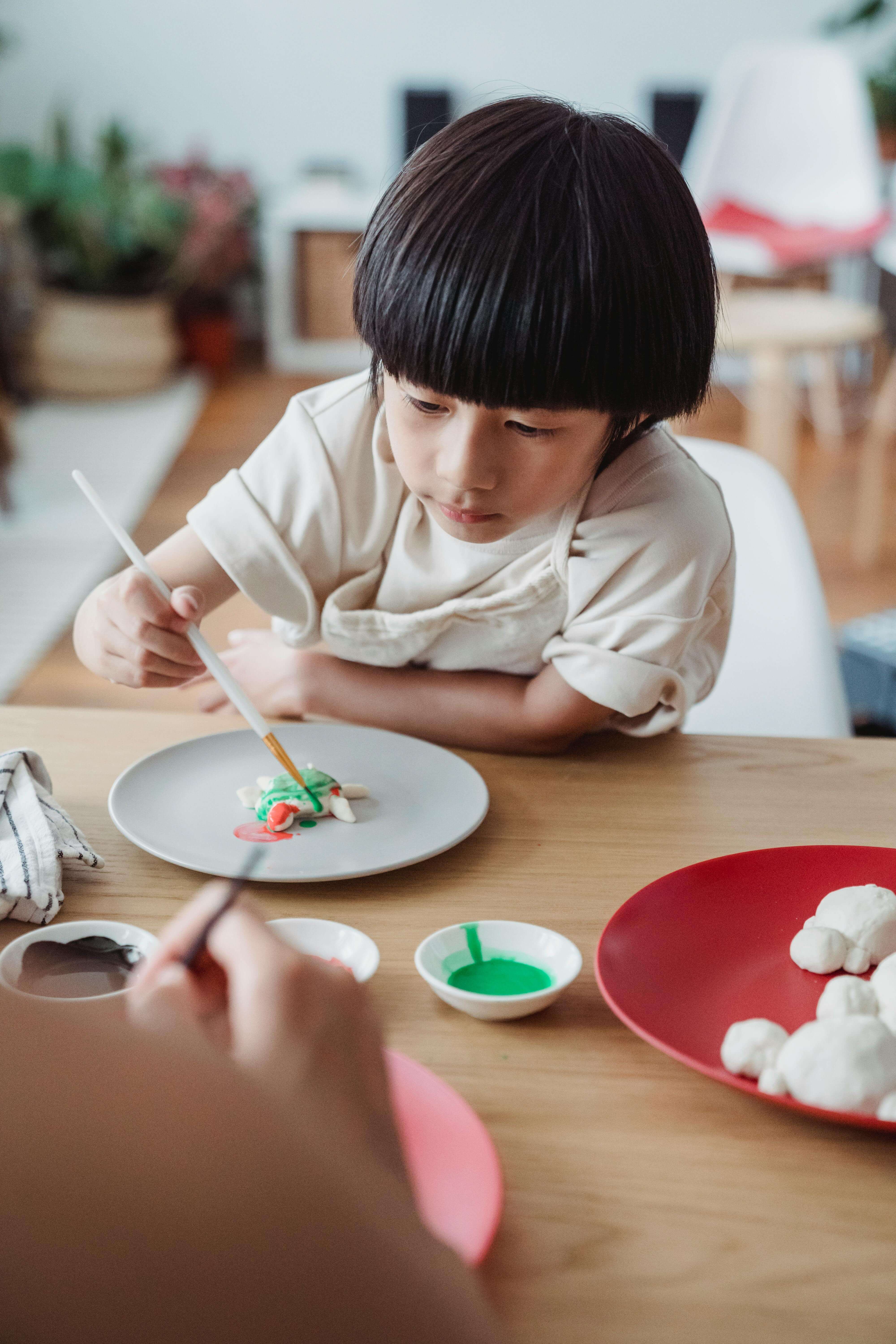 아이가 책상에 앉아 집중해서 작품을 만들고 있는 모습