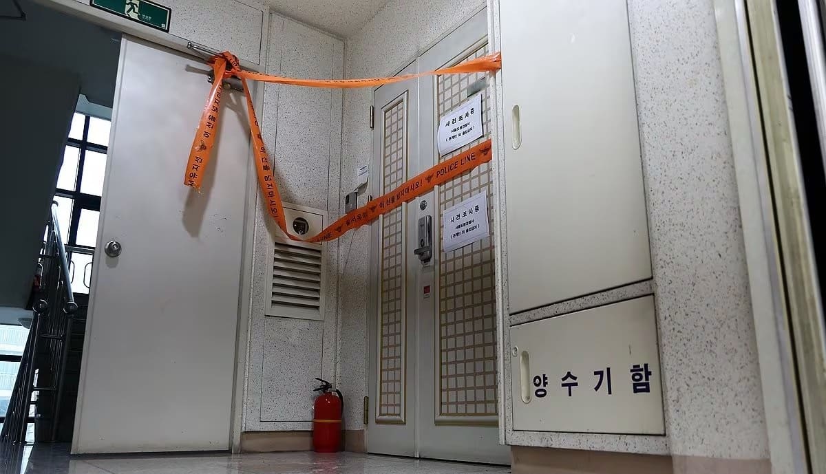 A police line is set up at the residence of a suspect who fired a gun at a priest, killing his family.