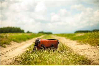 시골길 양옆과 길 가운데에는 풀이 잔디처럼 나있고, 가운데 가방하나가 놓여져 있는 사진