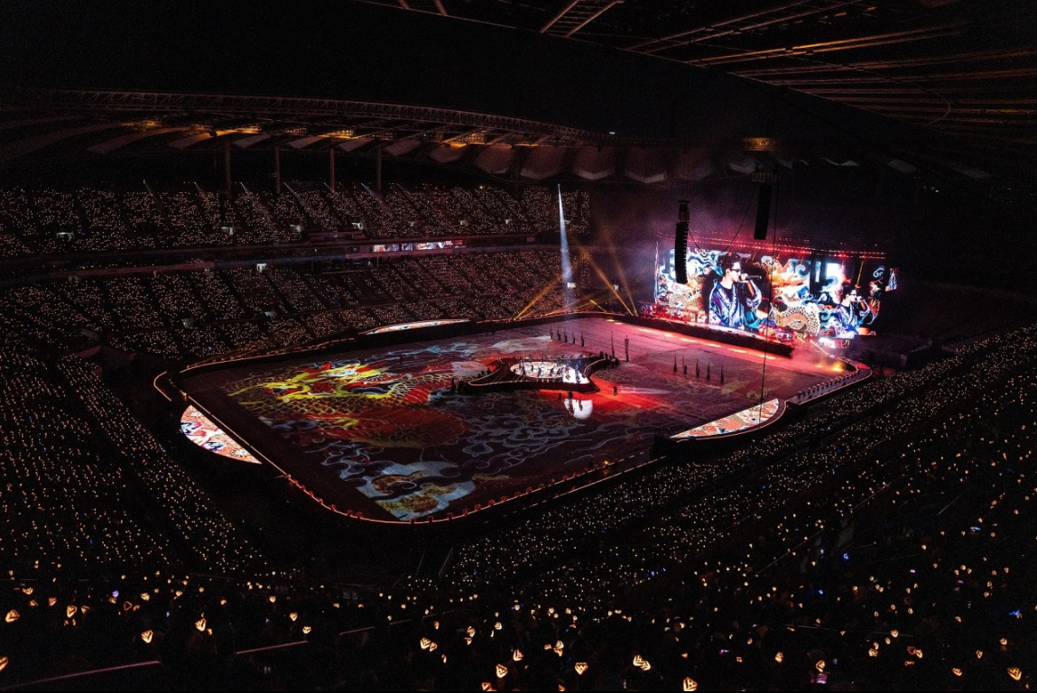 임영웅 콘서트 영화의 한 장면. 붉은 조명과 동양 문양의 조명이 무대를 비추고 있다.