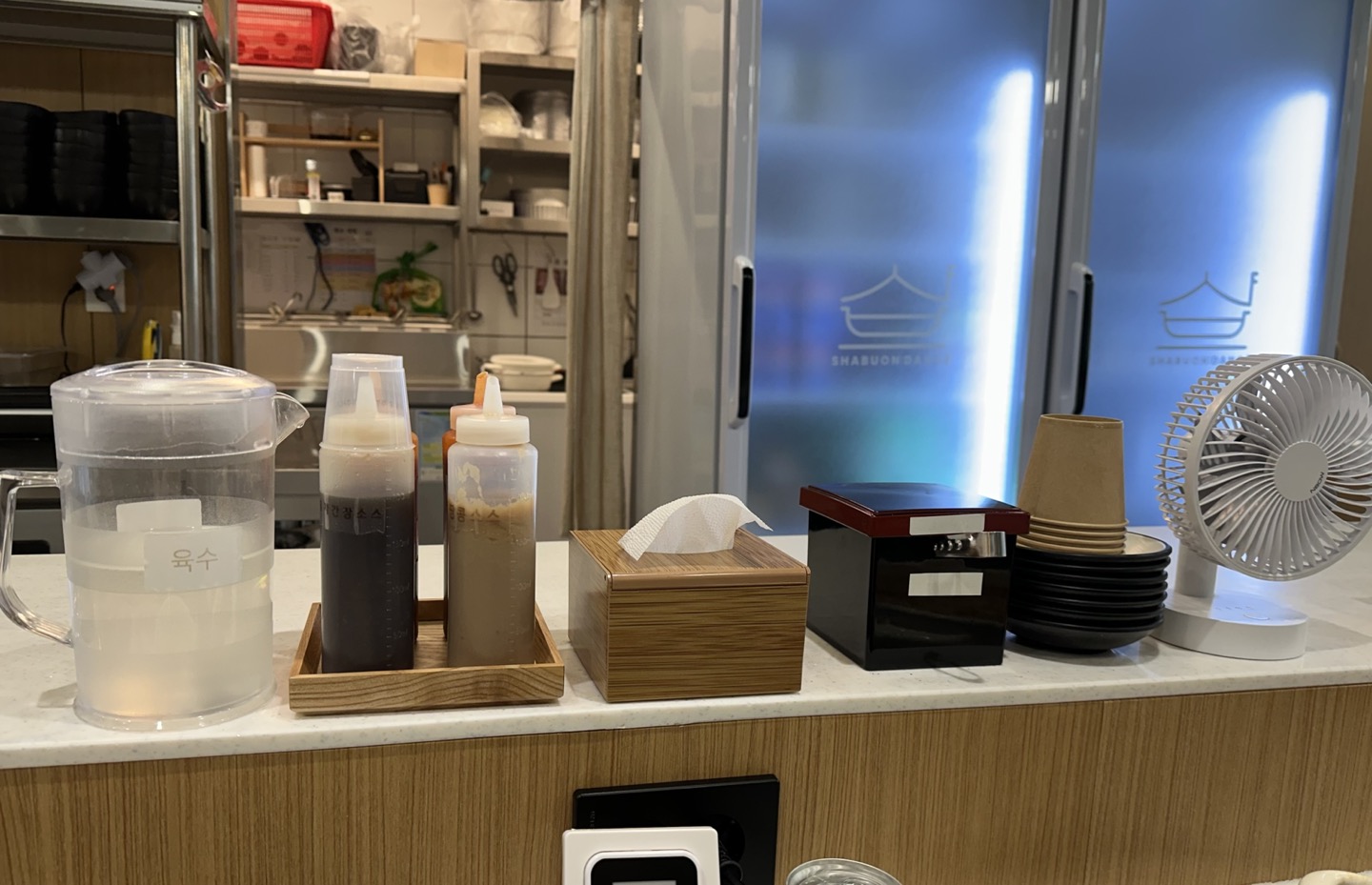 샤브온당 매장에 육수 및 소스&amp;#44; 컵&amp;#44; 그릇등이 비치된 이미지