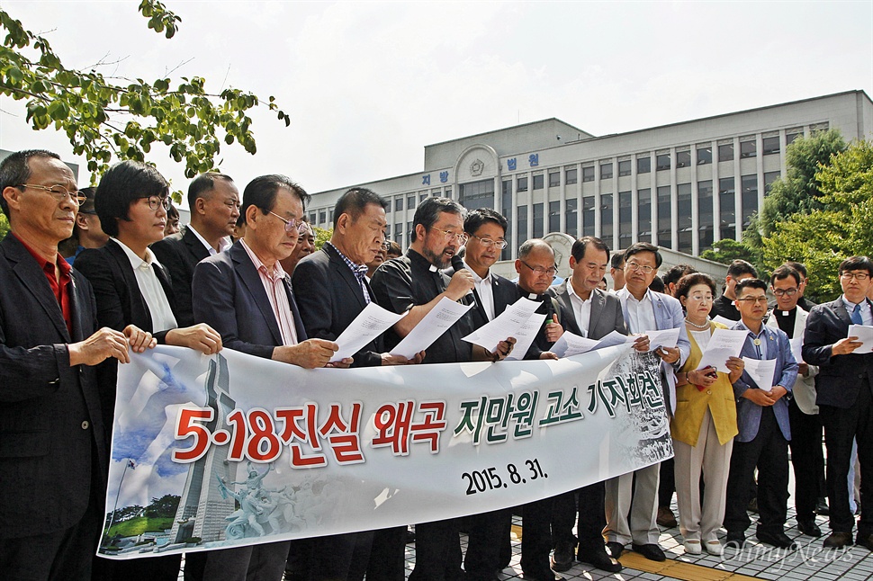 지만원 고소 관련 현수막 앞에서 문서를 읽는 참석자들